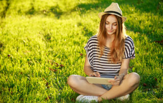 a woman sitting on grass looking at a tablet, weed allergy